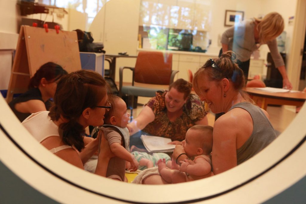 A small group of mothers and babies are gathered in a room